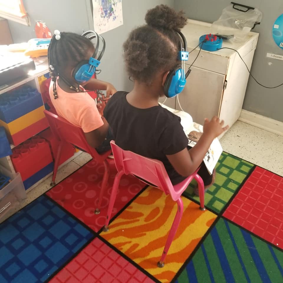 Two children wearing headphones sitting in chairs
