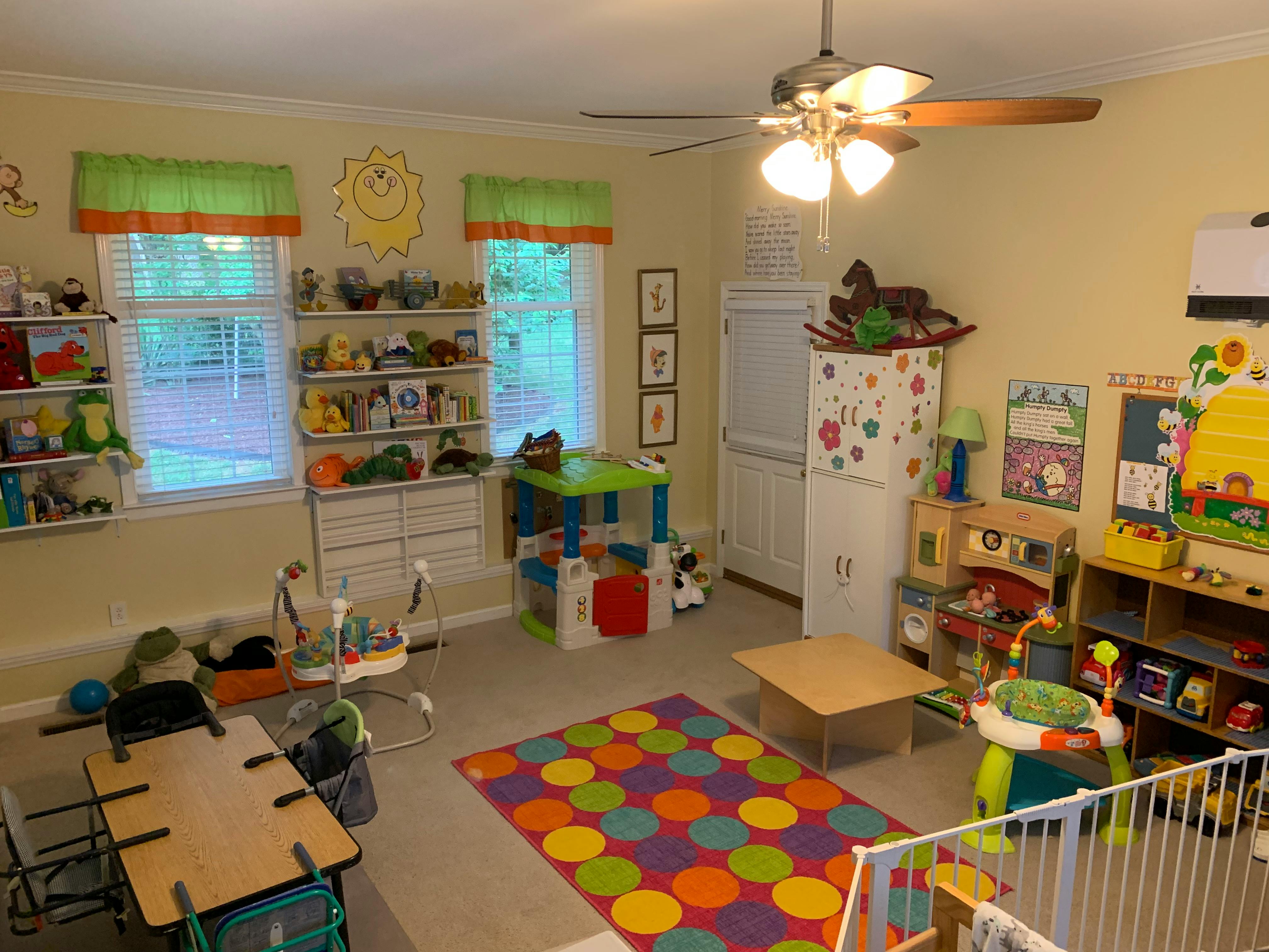 Playroom with colorful rug, small tables, and shelves filled with toys