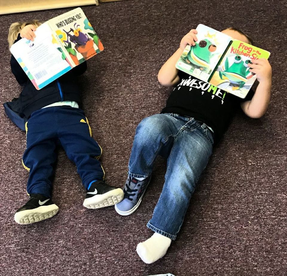 Two children lying on the floor reading books
