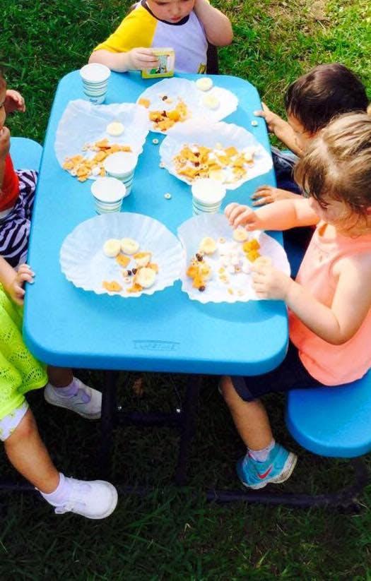 Children eating snacks at a blue picnic table outdoors