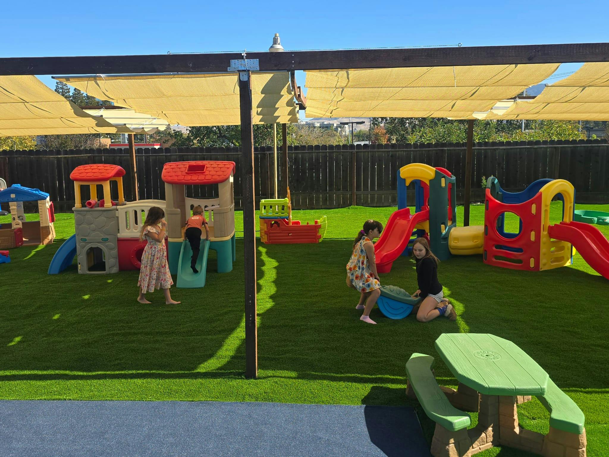 Children playing on various plastic play equipment at an outdoor playground