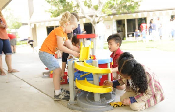 Children playing with a toy car ramp