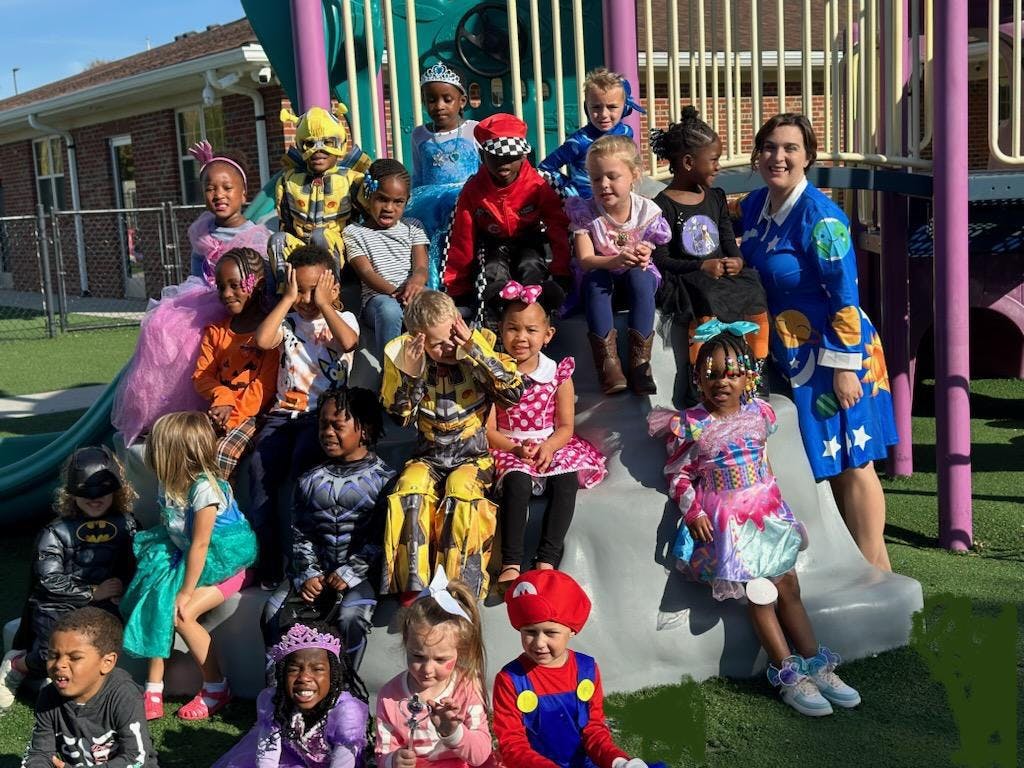 Group of children and one adult in costumes on a playground slide