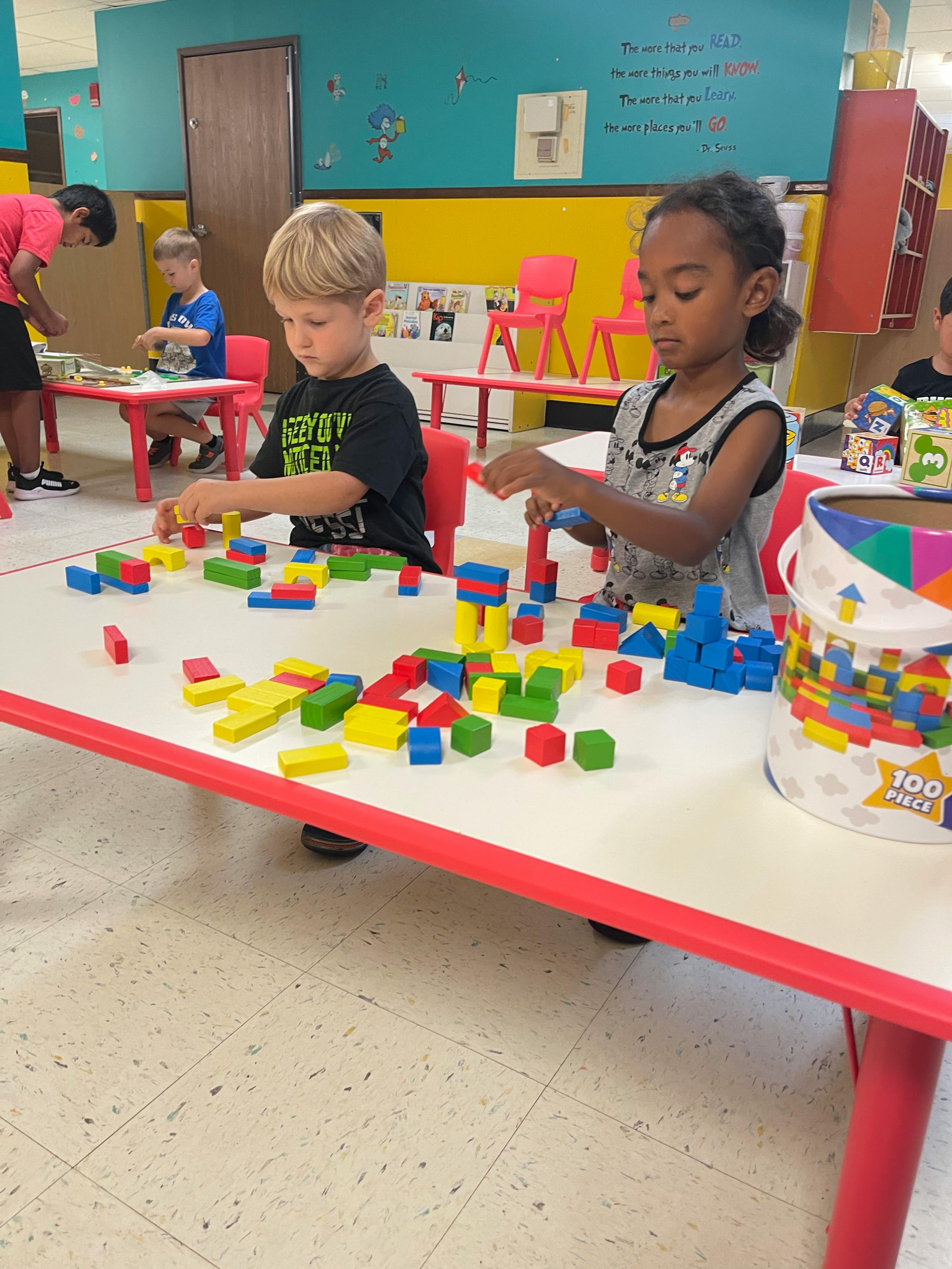 Two children playing with colorful building blocks at a table