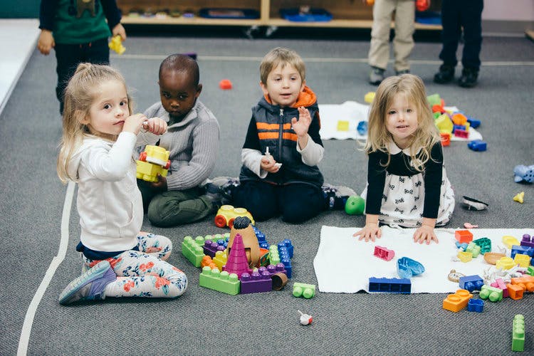 Four children playing with building blocks on the floor