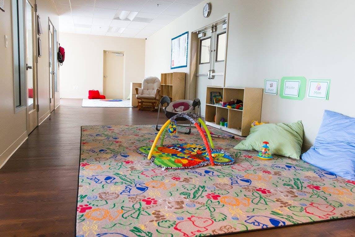 Playroom with colorful rug, baby play mat, and pillows