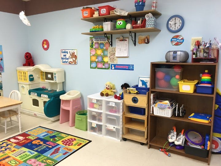 Playroom with shelves of toys, a play kitchen, and a colorful rug
