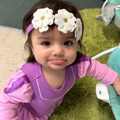 Child wearing a flower headband and purple outfit