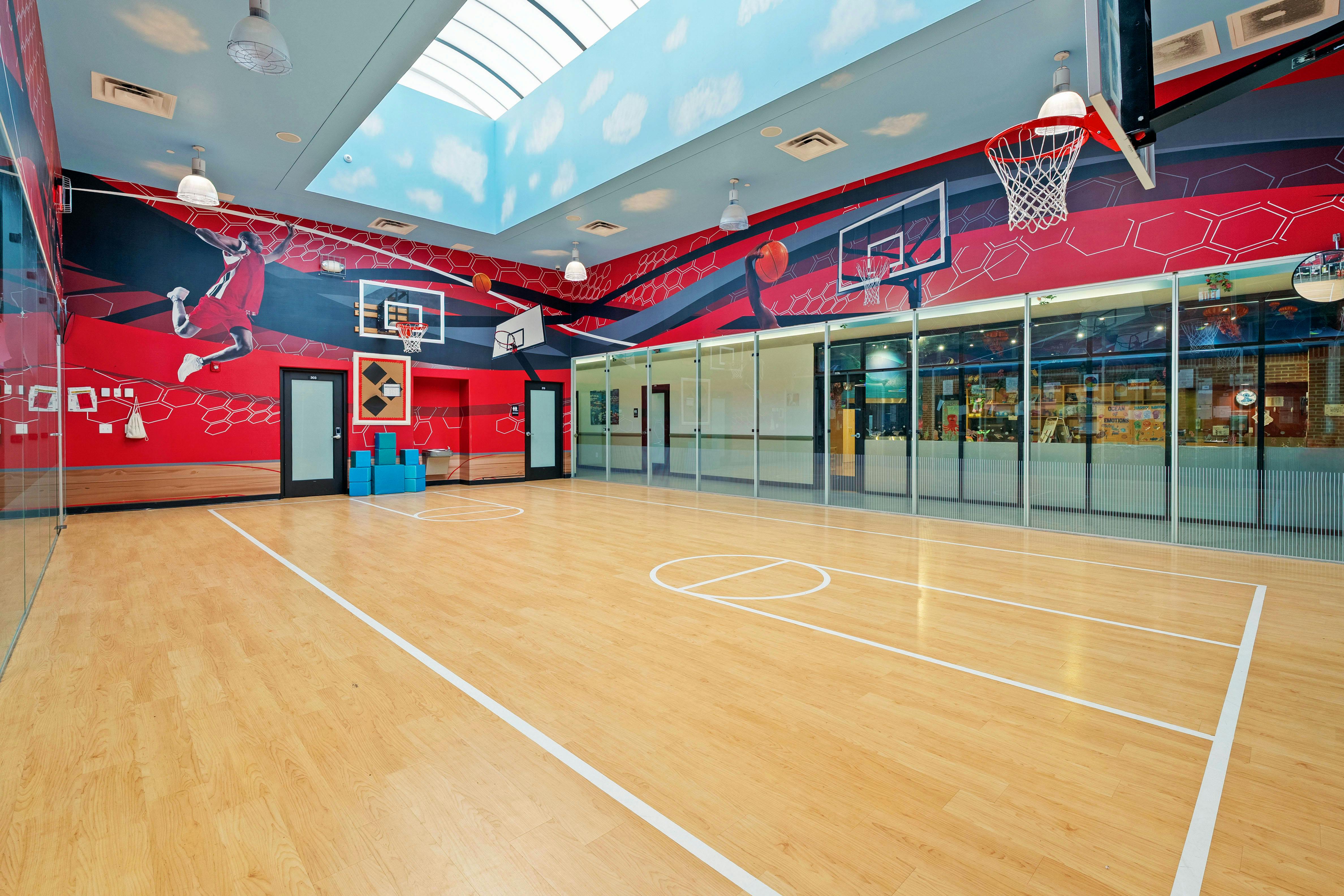 Indoor basketball court with red walls and mural of person playing basketball