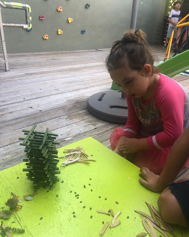 Child looking at a stack of green building blocks on a table