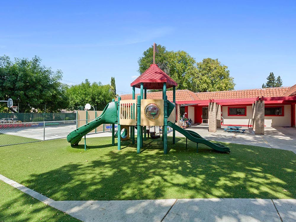 Playground with slides on artificial turf in front of a building