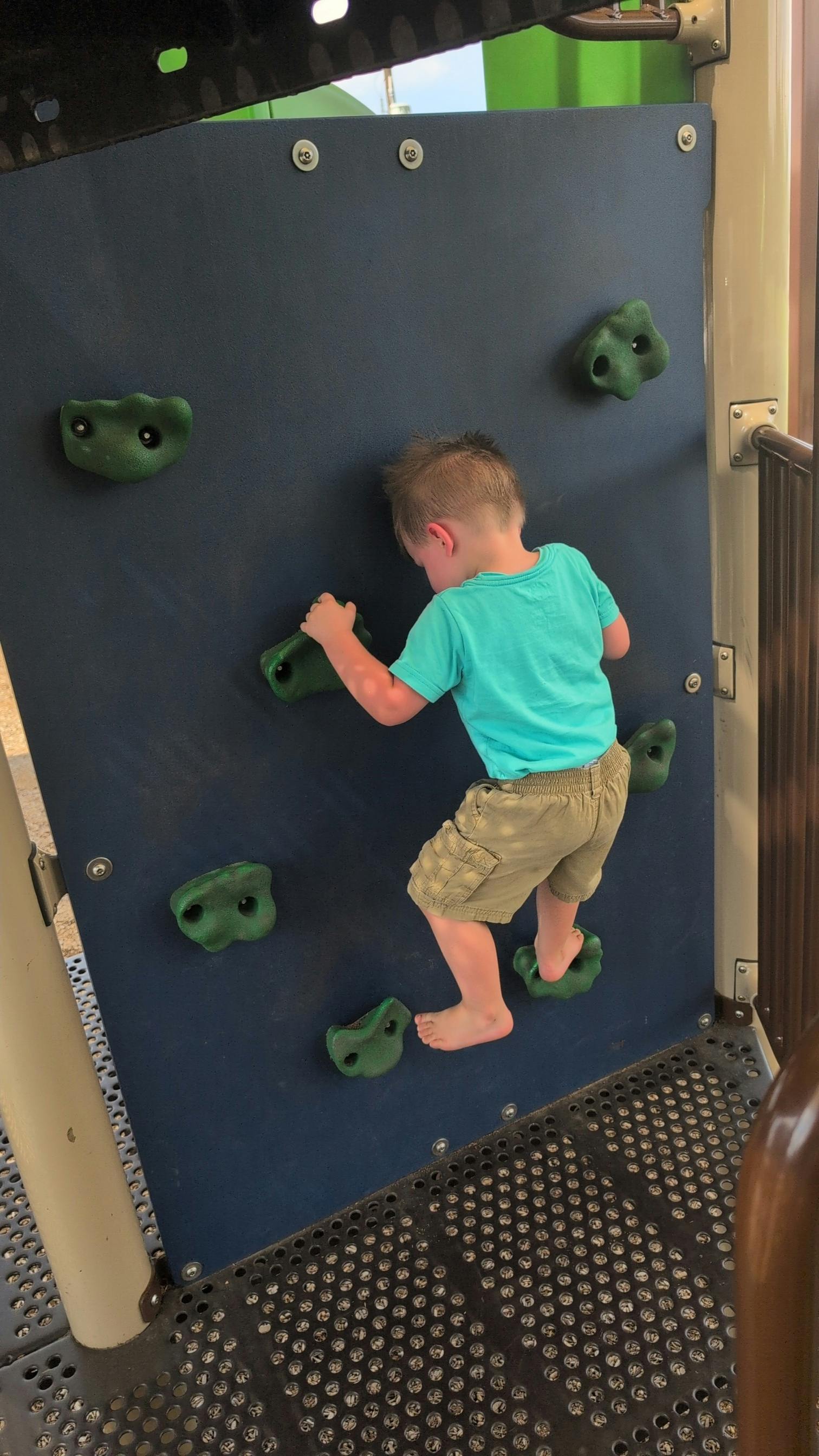 Child climbing a rock wall on a playground