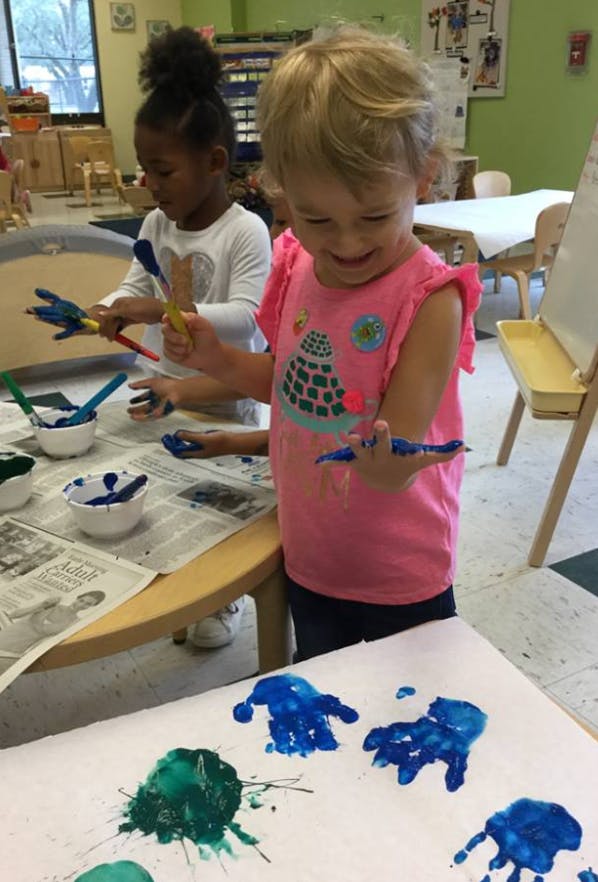 Two children painting with their hands in a classroom