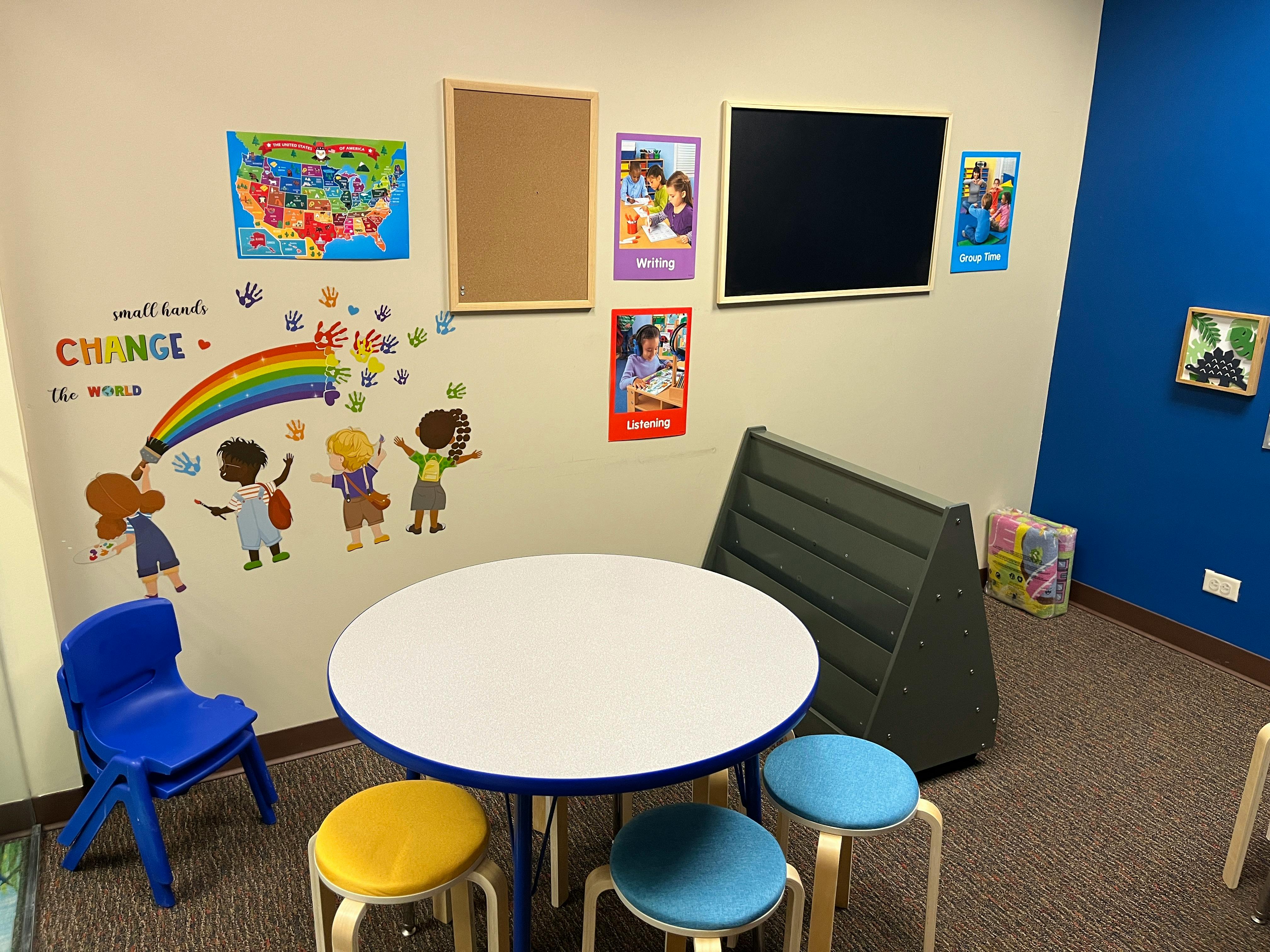 Children's classroom with a round table, stools, and wall decorations