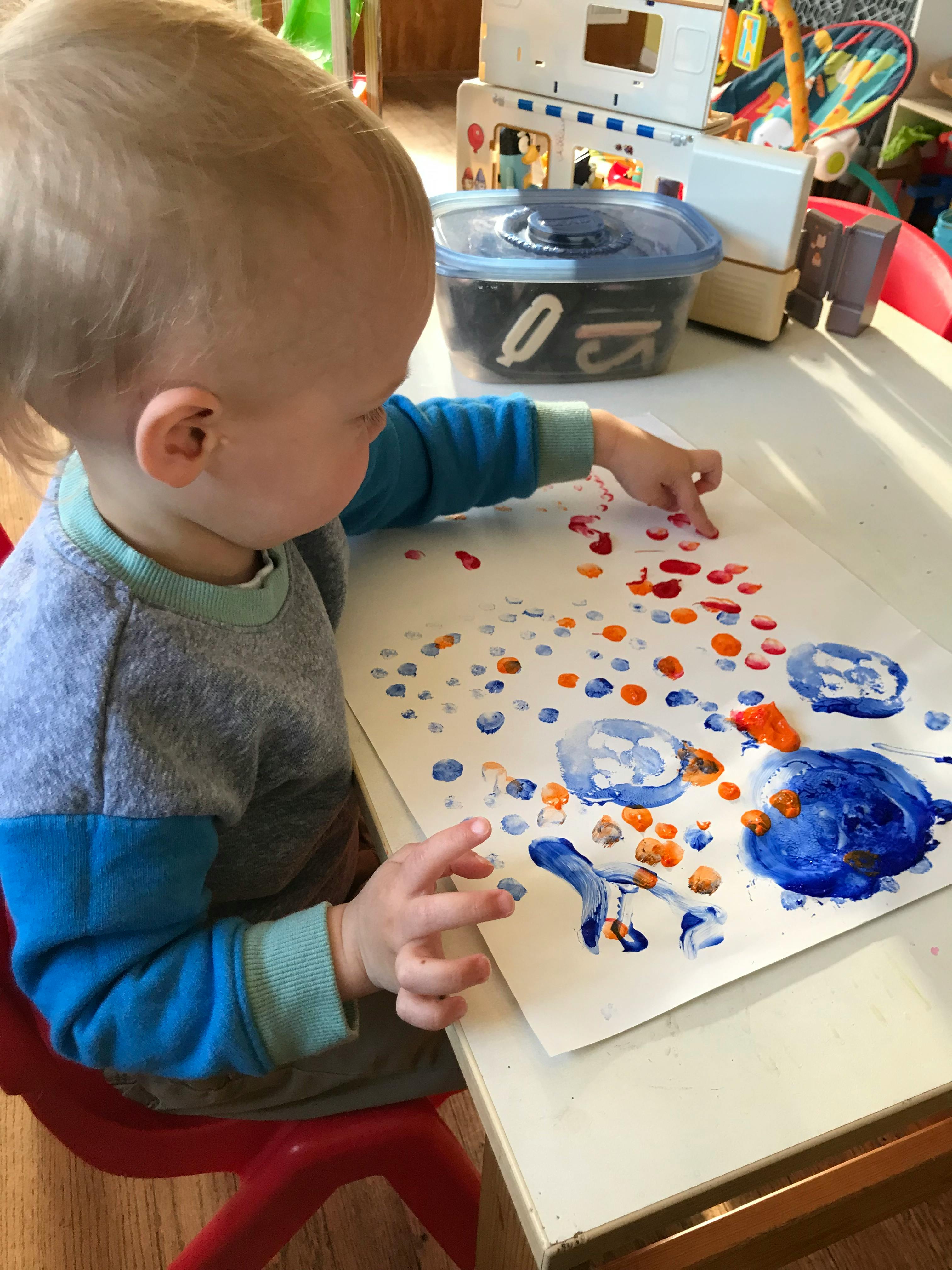 Child finger painting on paper at a table