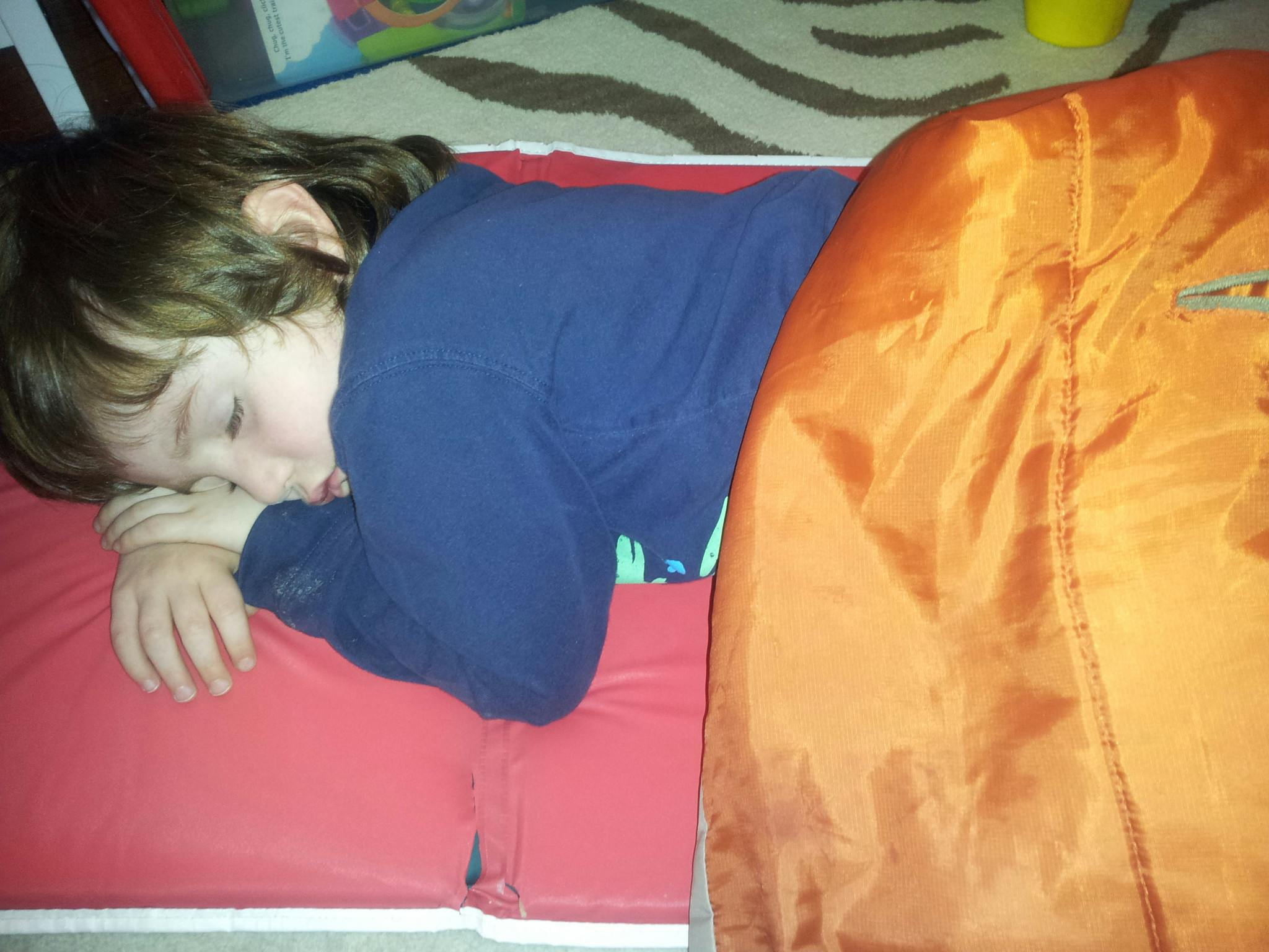 Child sleeping on a red mat