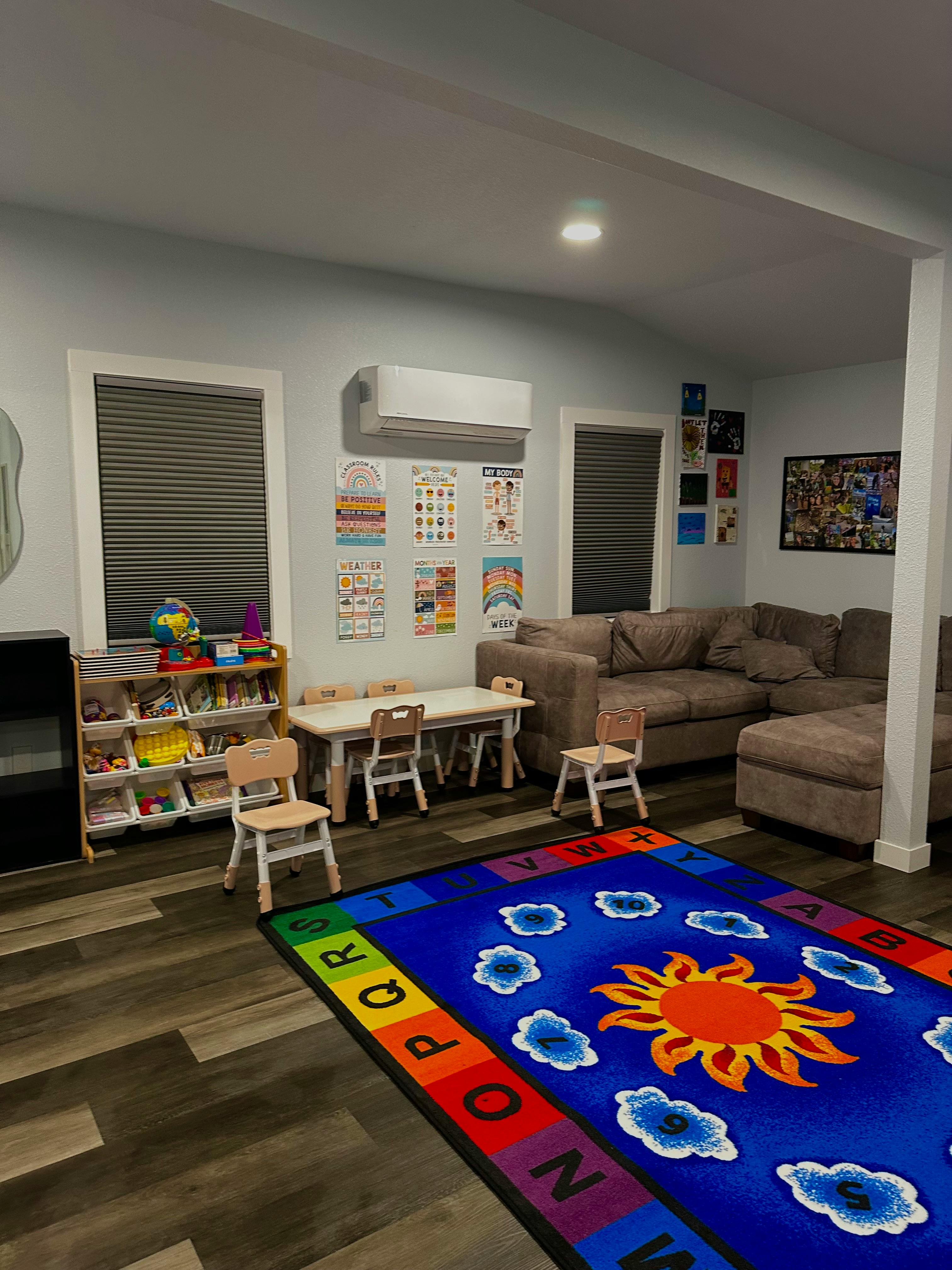 Playroom with a colorful rug, small table and chairs, and a sectional sofa