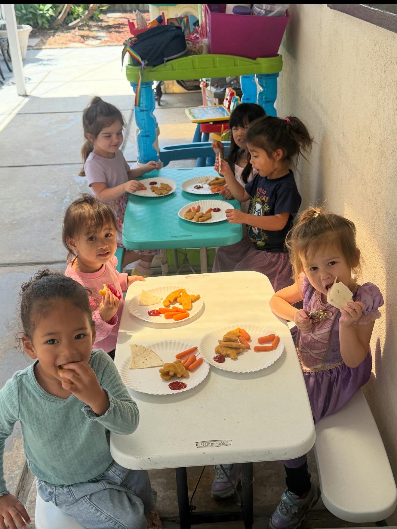 Group of children eating lunch at small tables