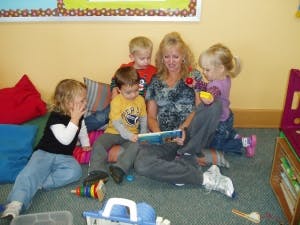 Adult and four children sitting on floor reading a book