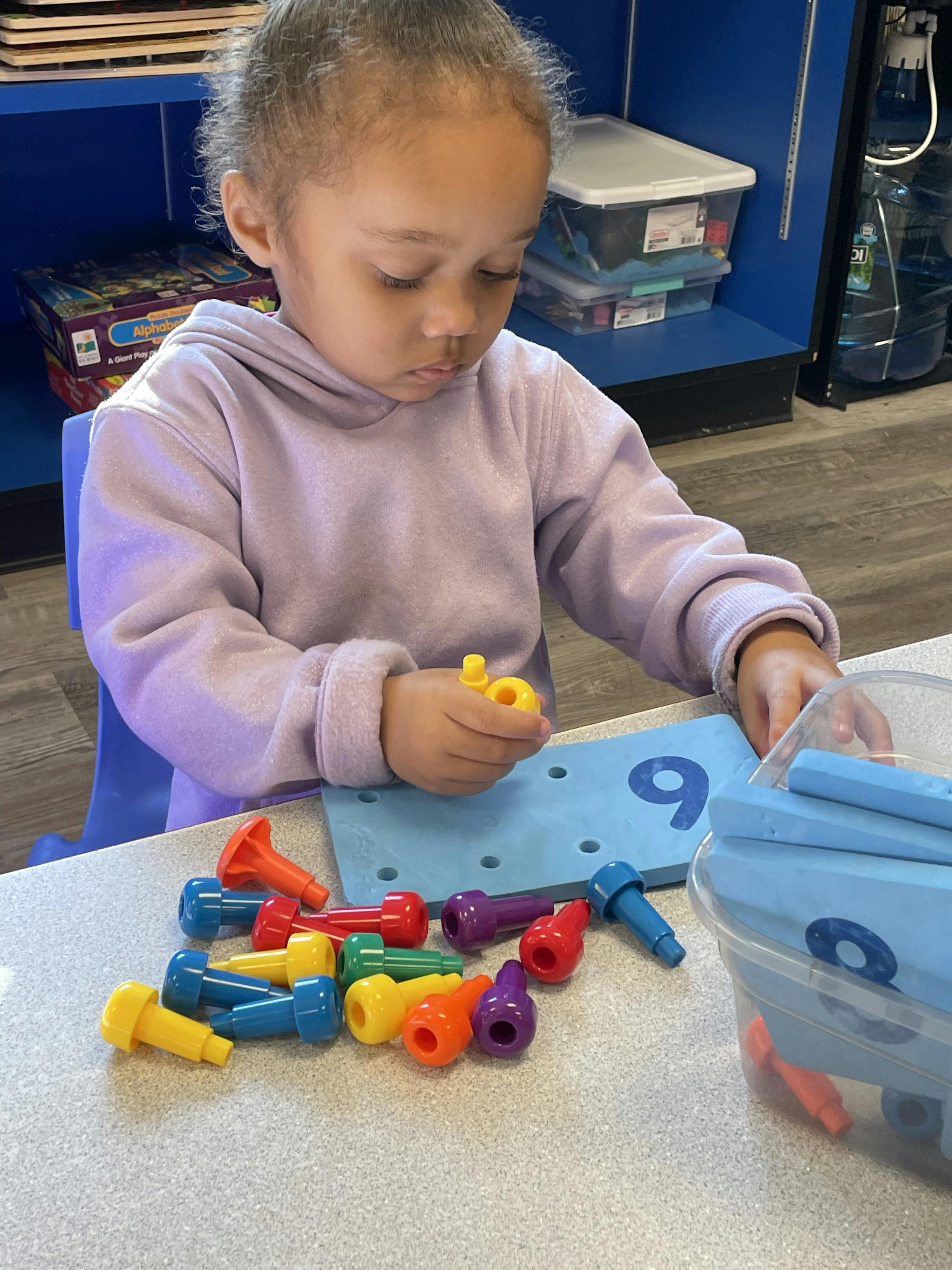 Child playing with colorful pegs and a pegboard