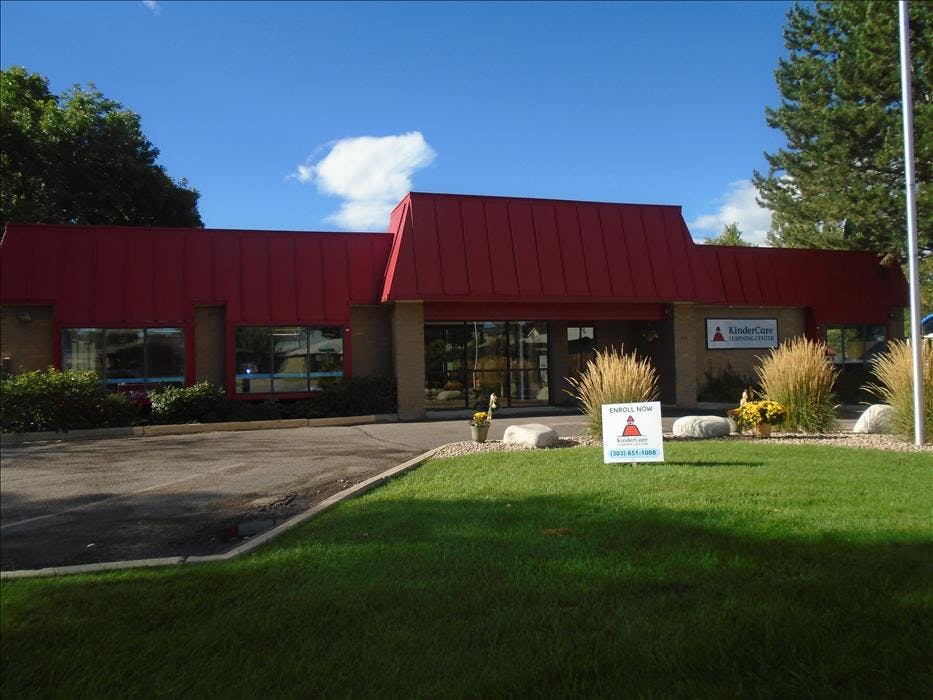 KinderCare Learning Center building with red roof and an "Enroll Now" sign