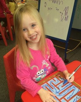 Child drawing a maze at a table