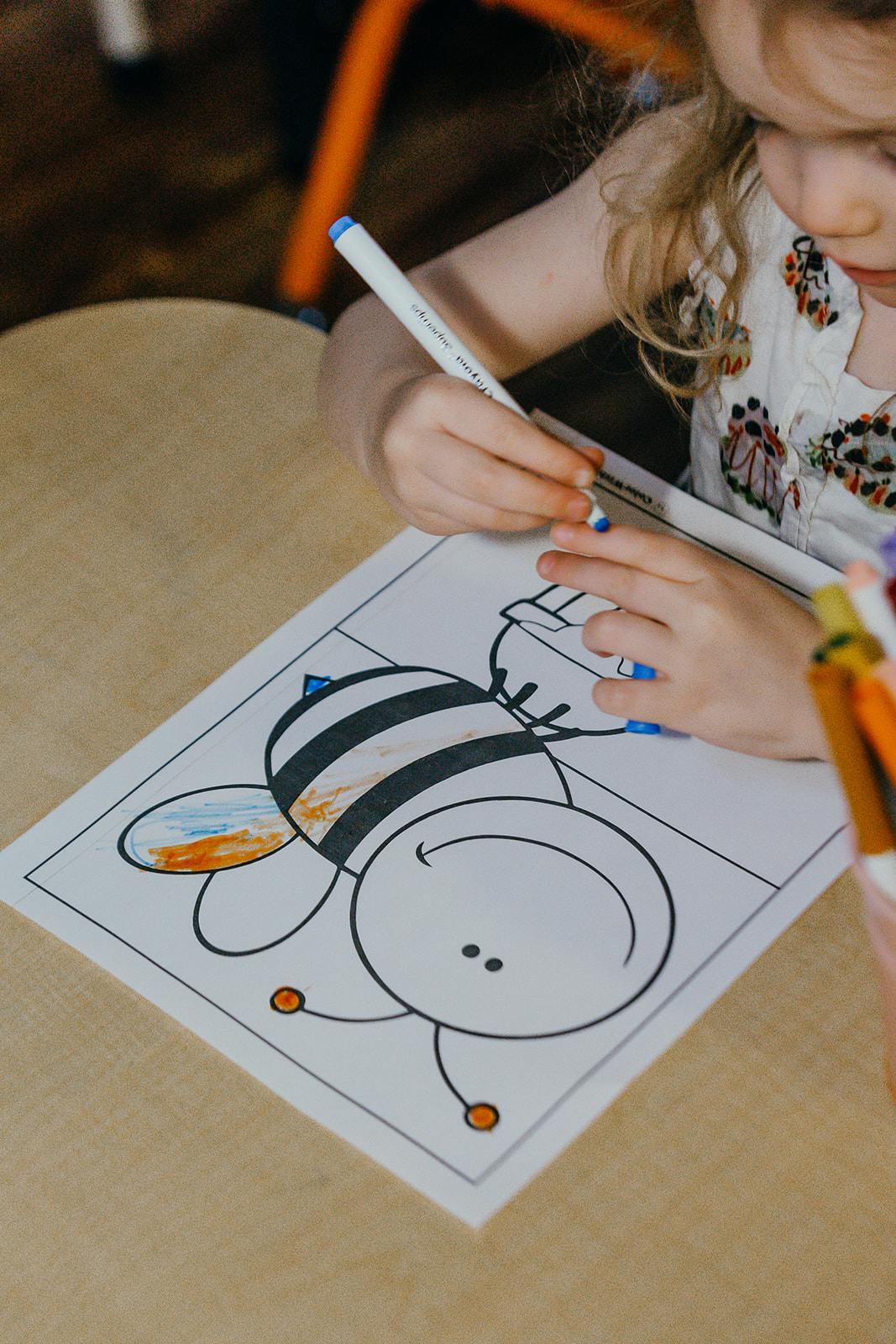 Child coloring a bee on a coloring page