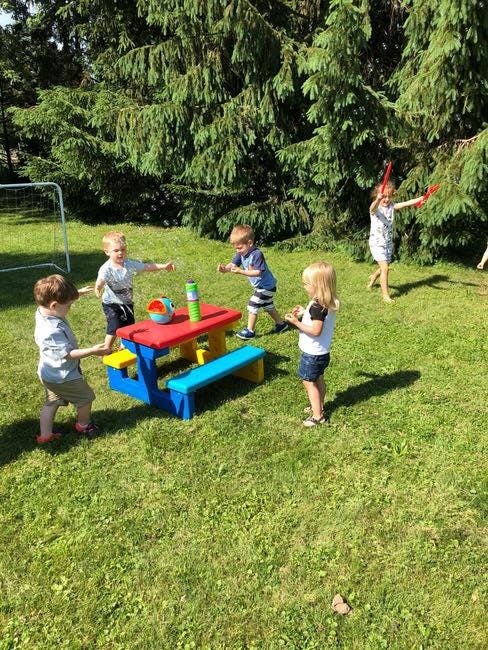 Children playing outdoors around a colorful picnic table