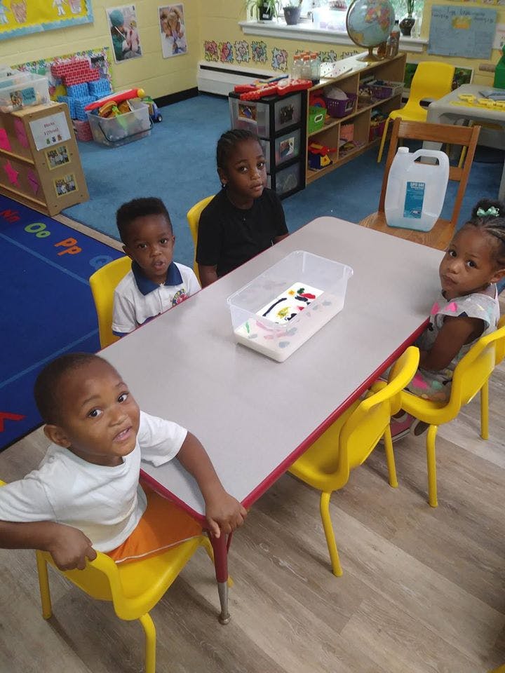 Four children sitting at a table in a classroom
