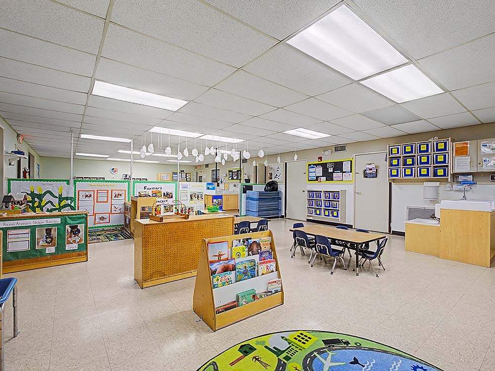 Classroom with tables, chairs, bookshelves, and decorations on the walls