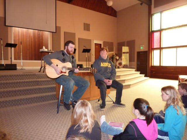 Person playing guitar for a group of people