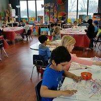 Children painting at tables in a classroom