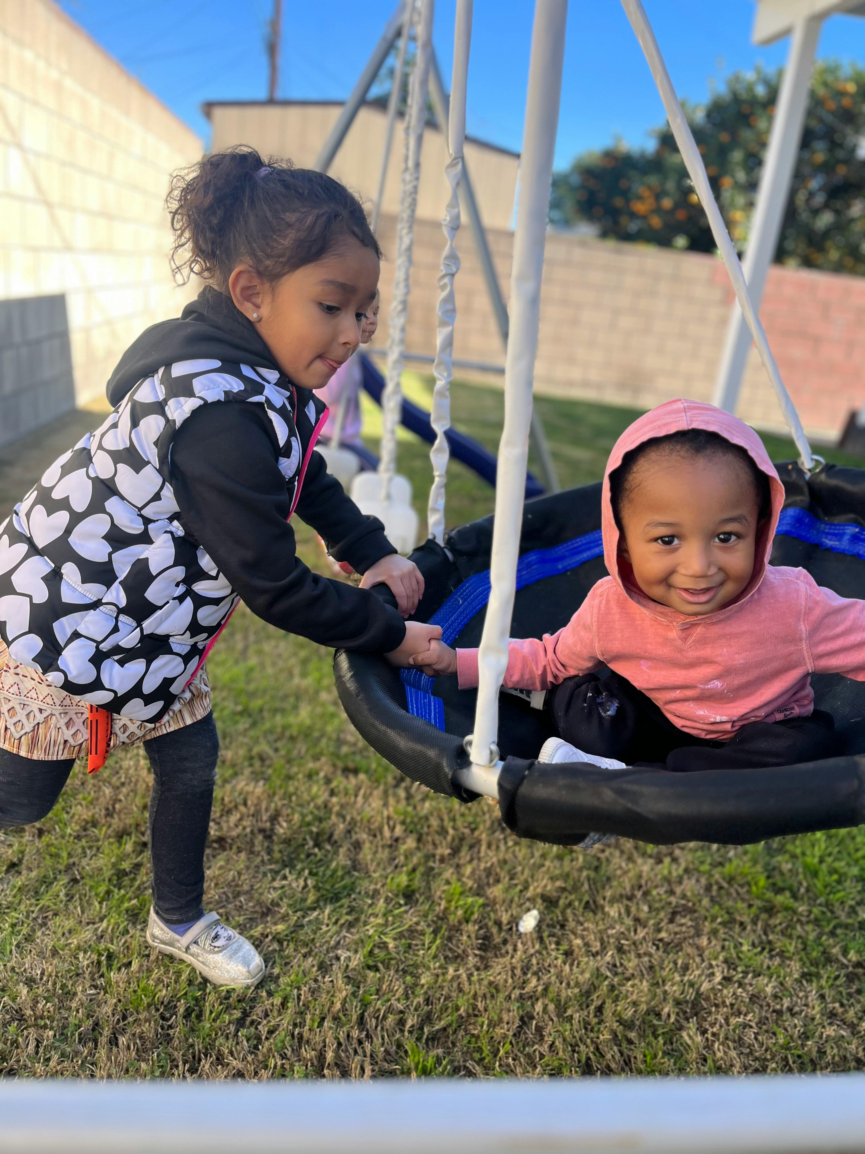 Child pushing another child in a swing