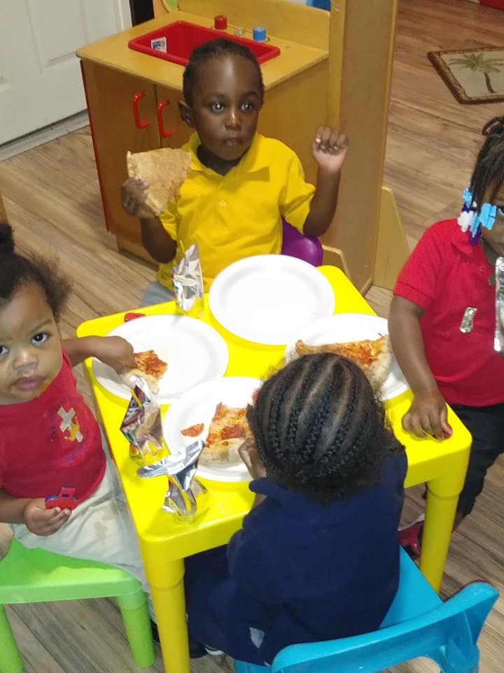 Children eating pizza at a yellow table