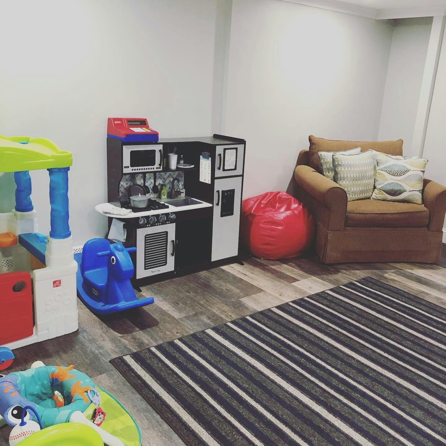 Playroom with a toy kitchen, rocking horse, and armchair