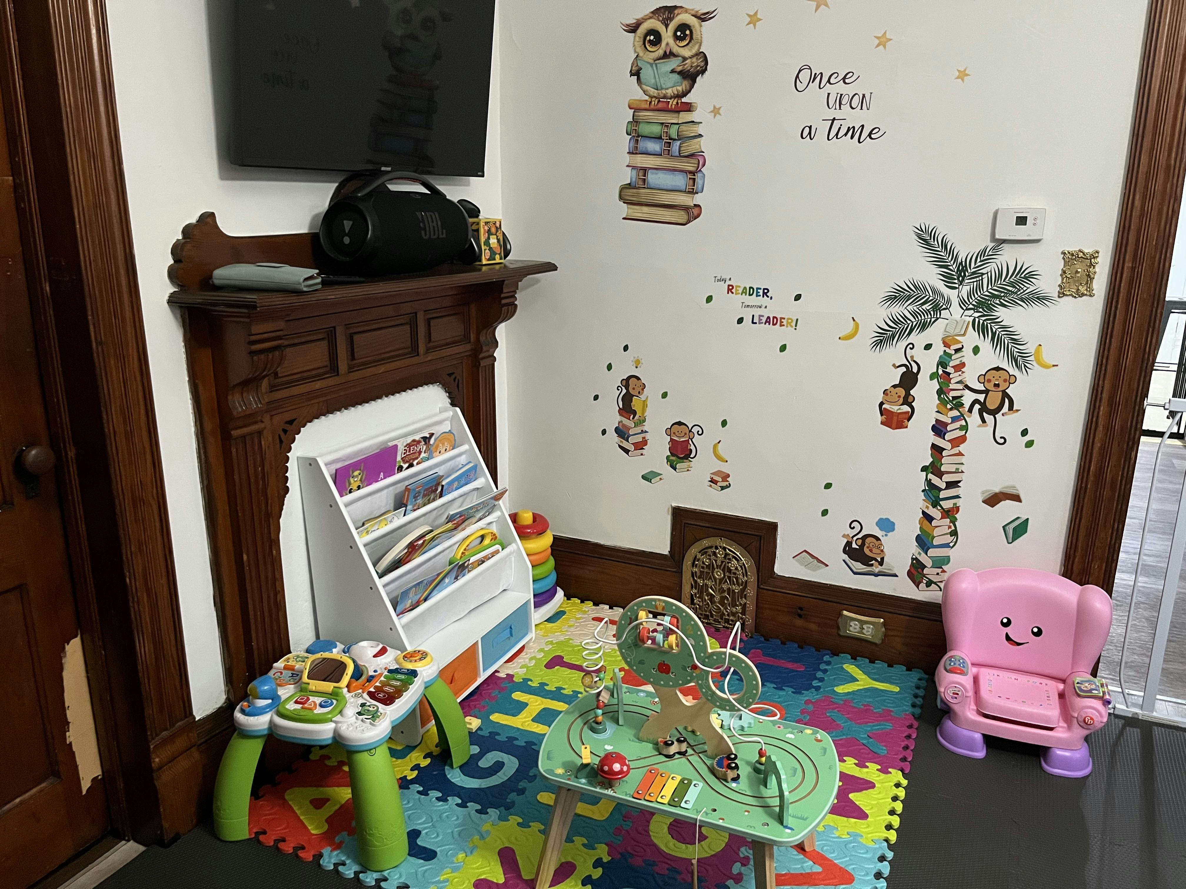 Children's play area with toys, book display, and wall decals