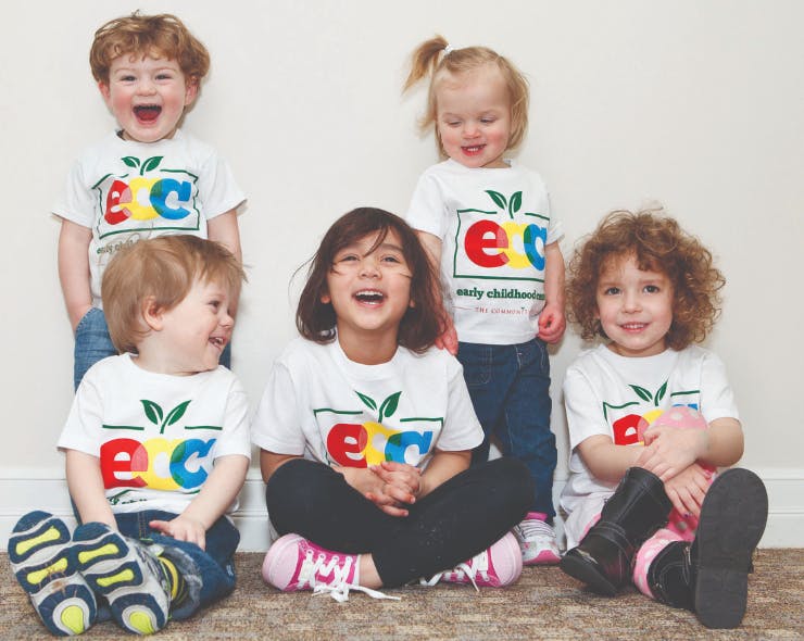 Five children wearing white t-shirts with a colorful logo
