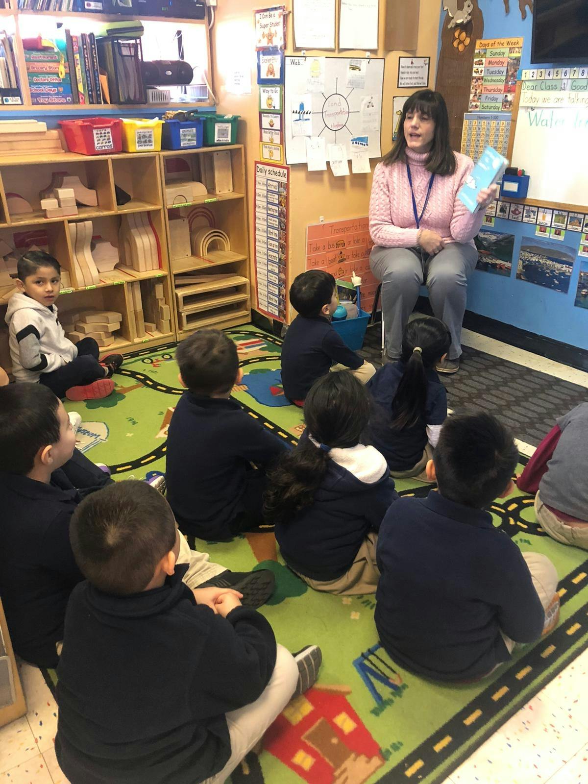 Adult reading to children sitting on a rug in a classroom