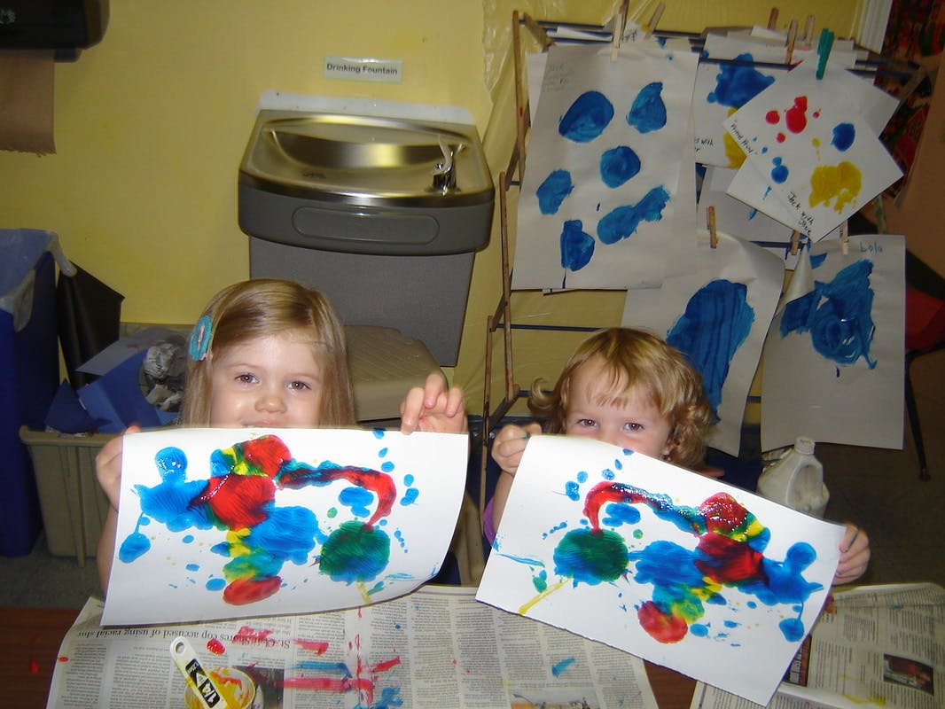 Two children holding up their colorful paintings