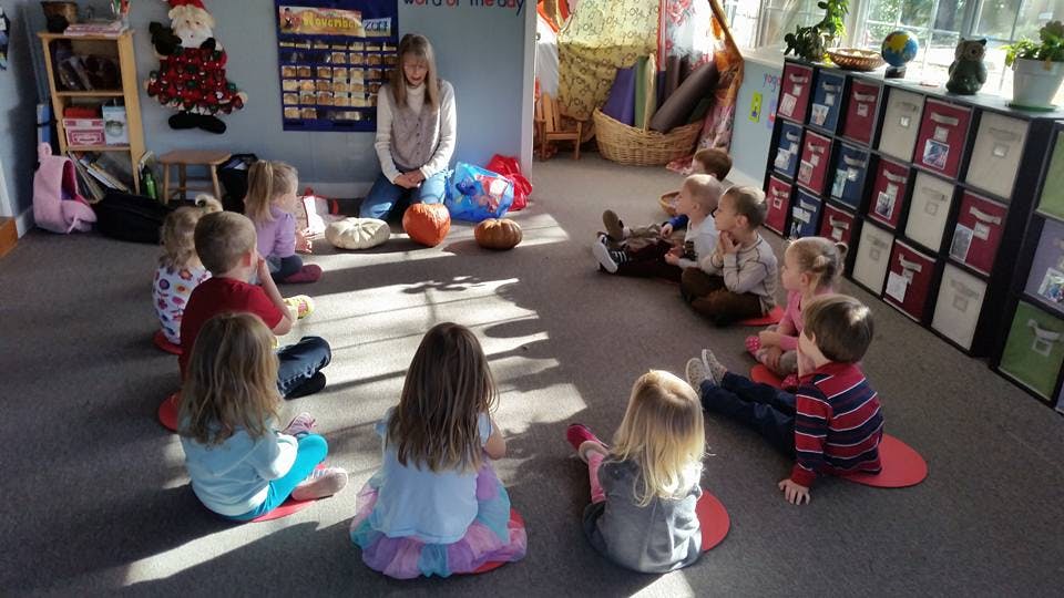 Person sitting on floor with children in a classroom