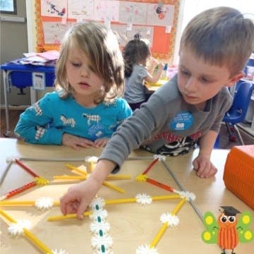 Two children playing with a building toy at a table
