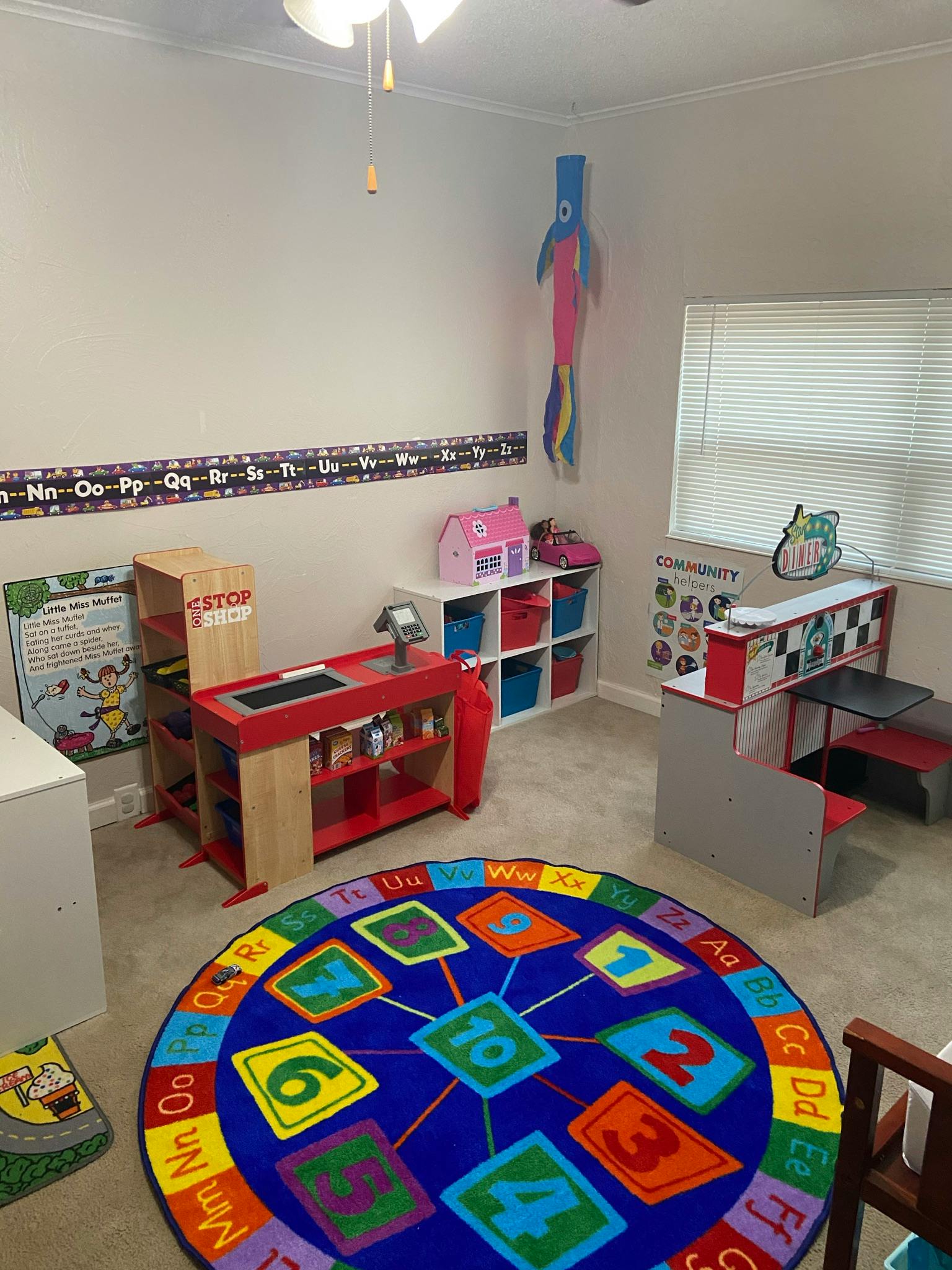 Playroom with a colorful alphabet and number rug, toy kitchen, and toy store