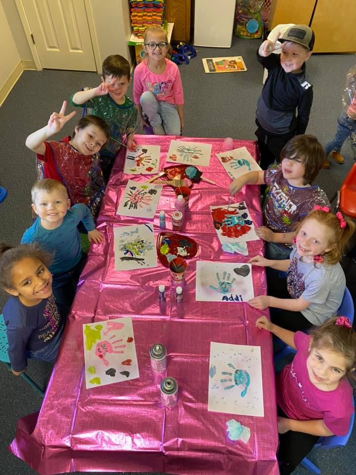 Group of children sitting around a table with art projects