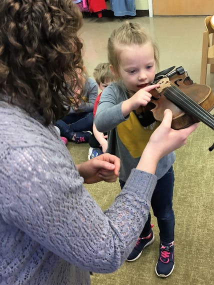 Adult holding a violin for a child to touch