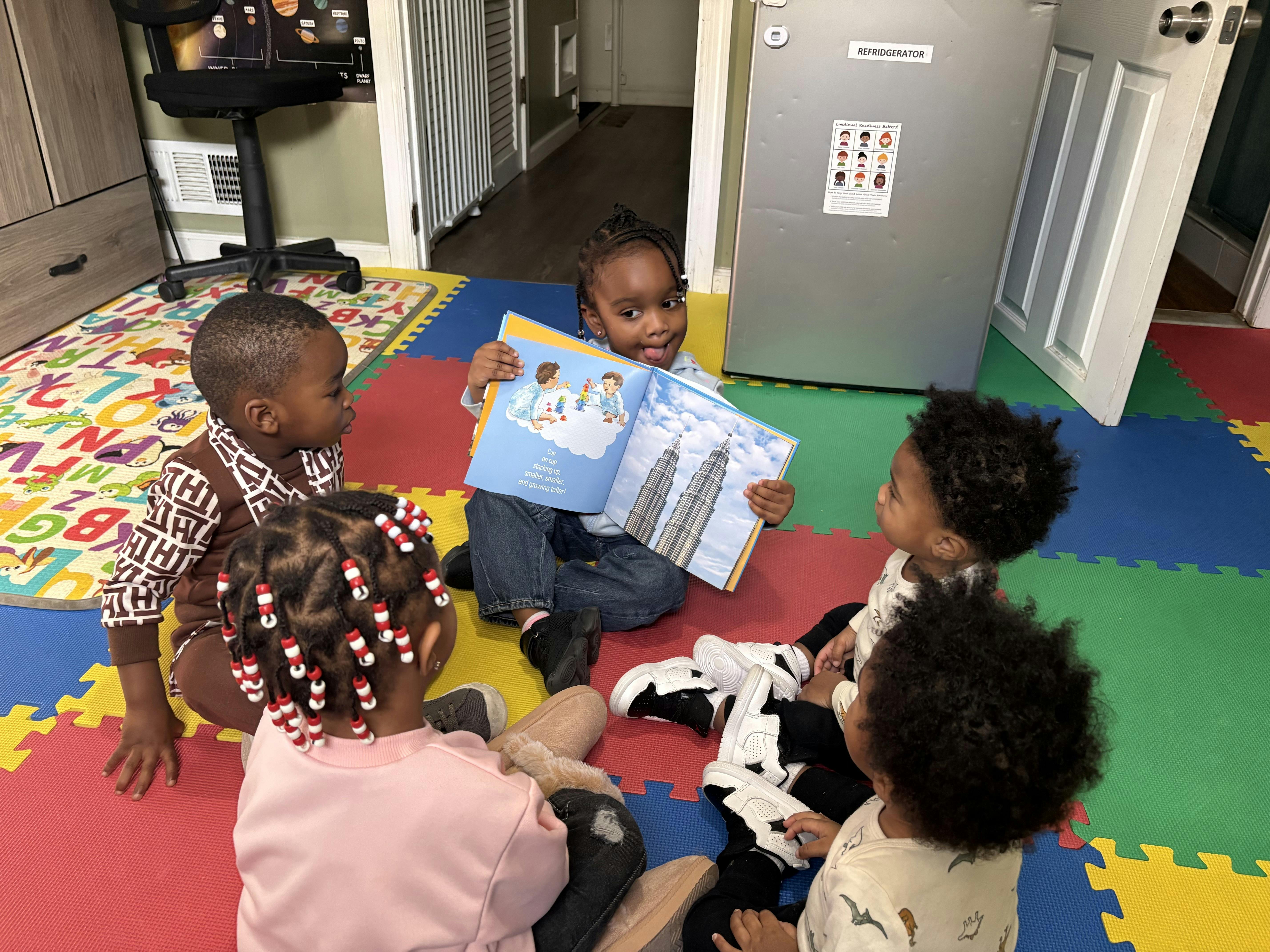 Child reading a picture book to other children in a classroom