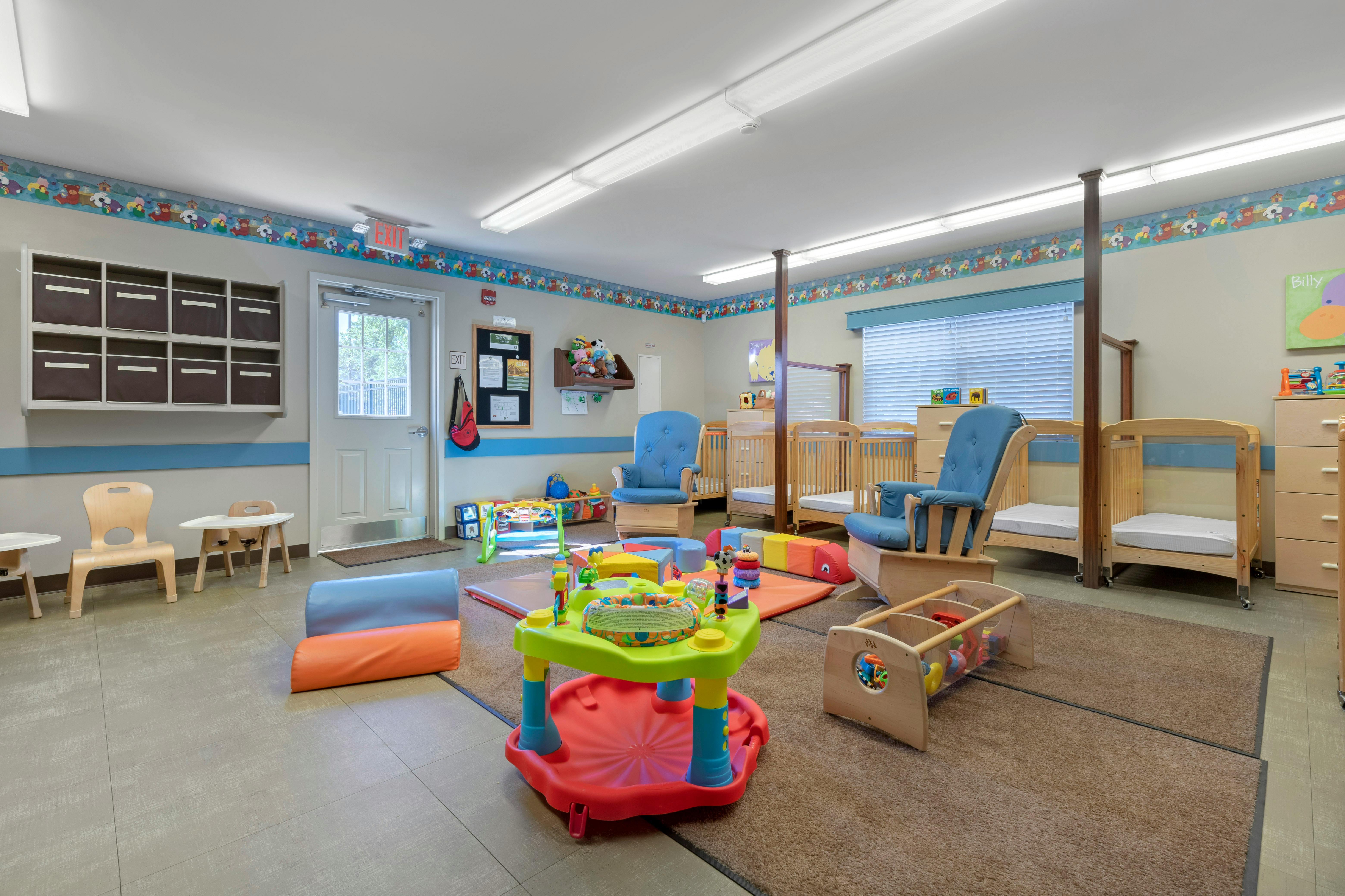 Classroom for babies with cribs, play mats, and activity tables