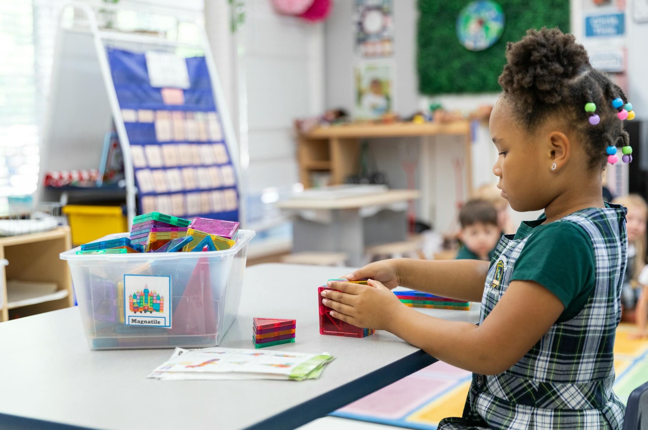 Child building with colorful magnetic tiles in a classroom