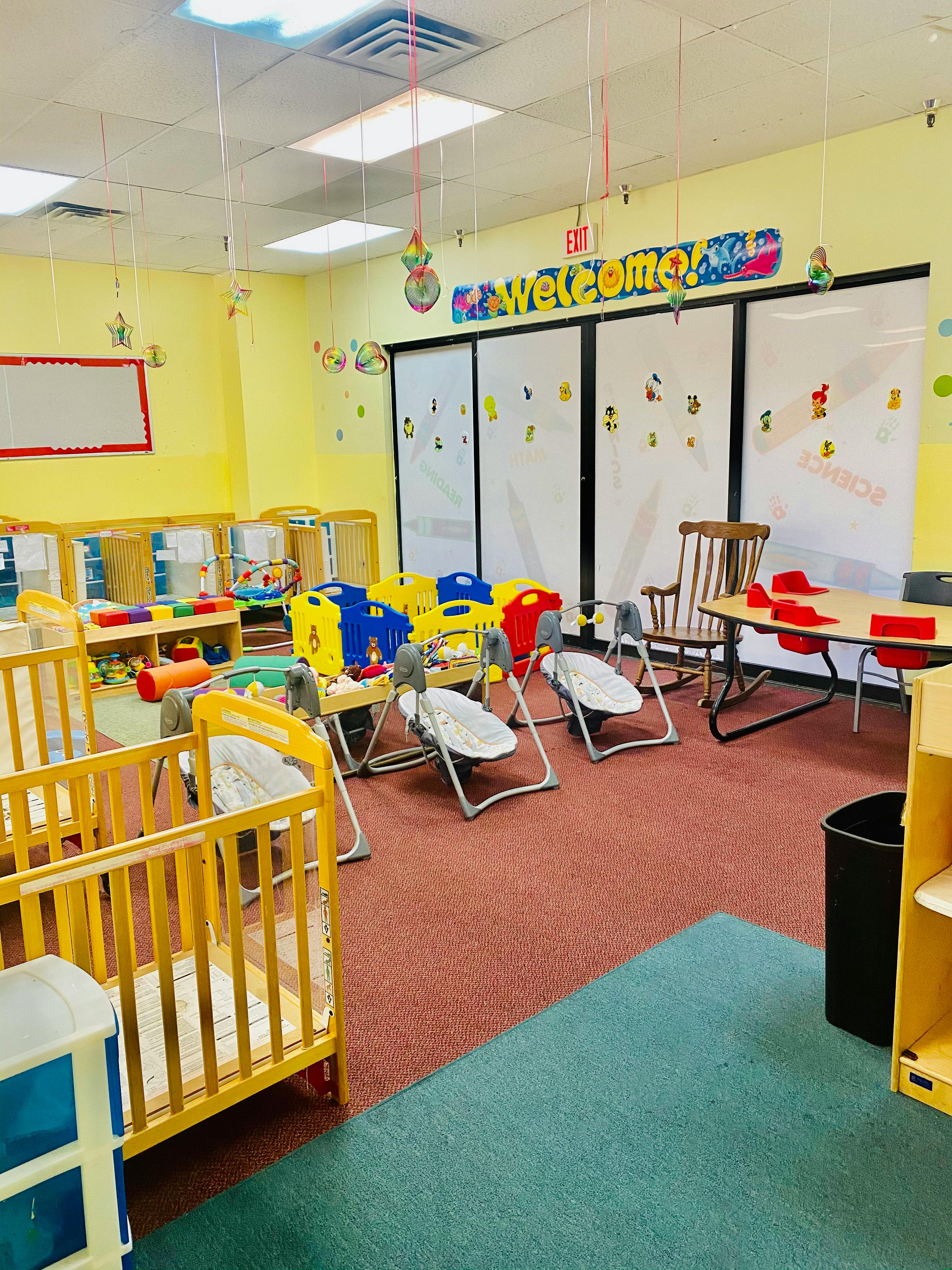 Infant room with cribs, swings, and a welcome sign