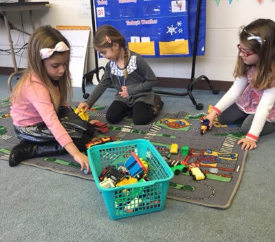Three children playing with toys on a rug