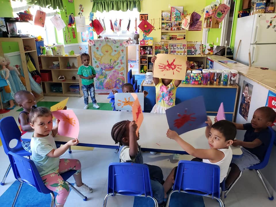 Children holding up artwork in a classroom